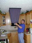 Technician testing airflow at a ceiling supply vent with a flow-measurement hood
